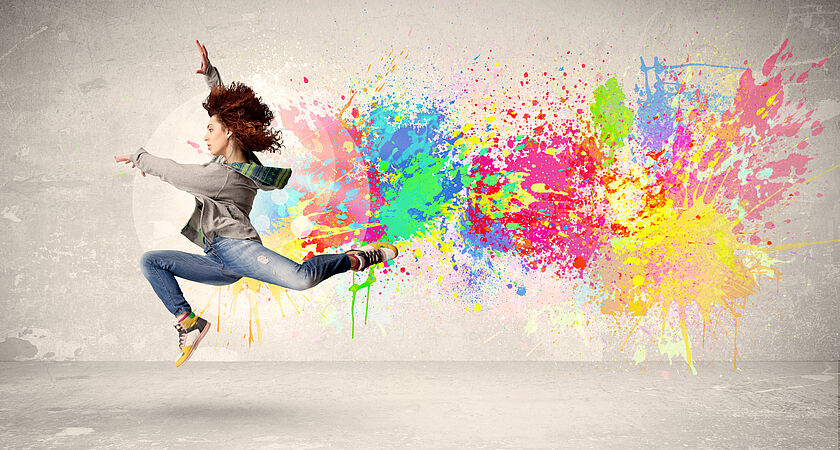 ein Teenager bei einem Tanzsprung vor einem Hintergrund mit bunten Farben